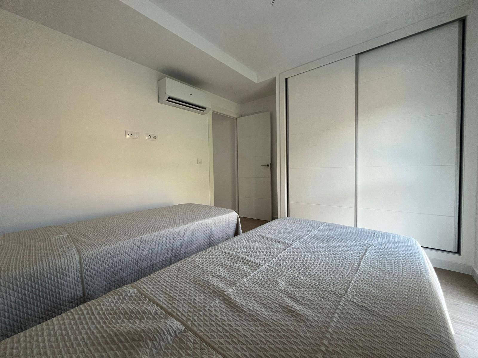 Schlafzimmer mit zwei Betten, Klimaanlage und integriertem Kleiderschrank.