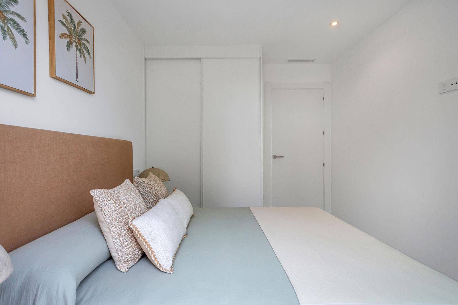 Schlafzimmer mit beigem Kopfteil und praktischen Einbauschränken für Stauraum.