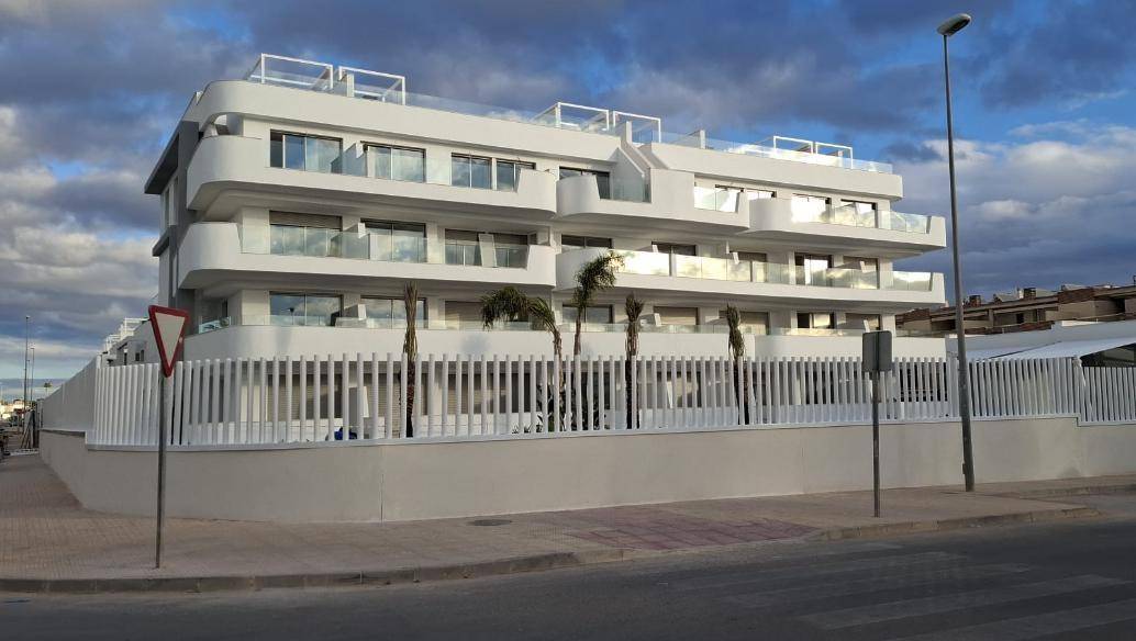 Elegante weiße Fassade eines modernen Apartmentgebäudes mit großen Glasbalkonen.