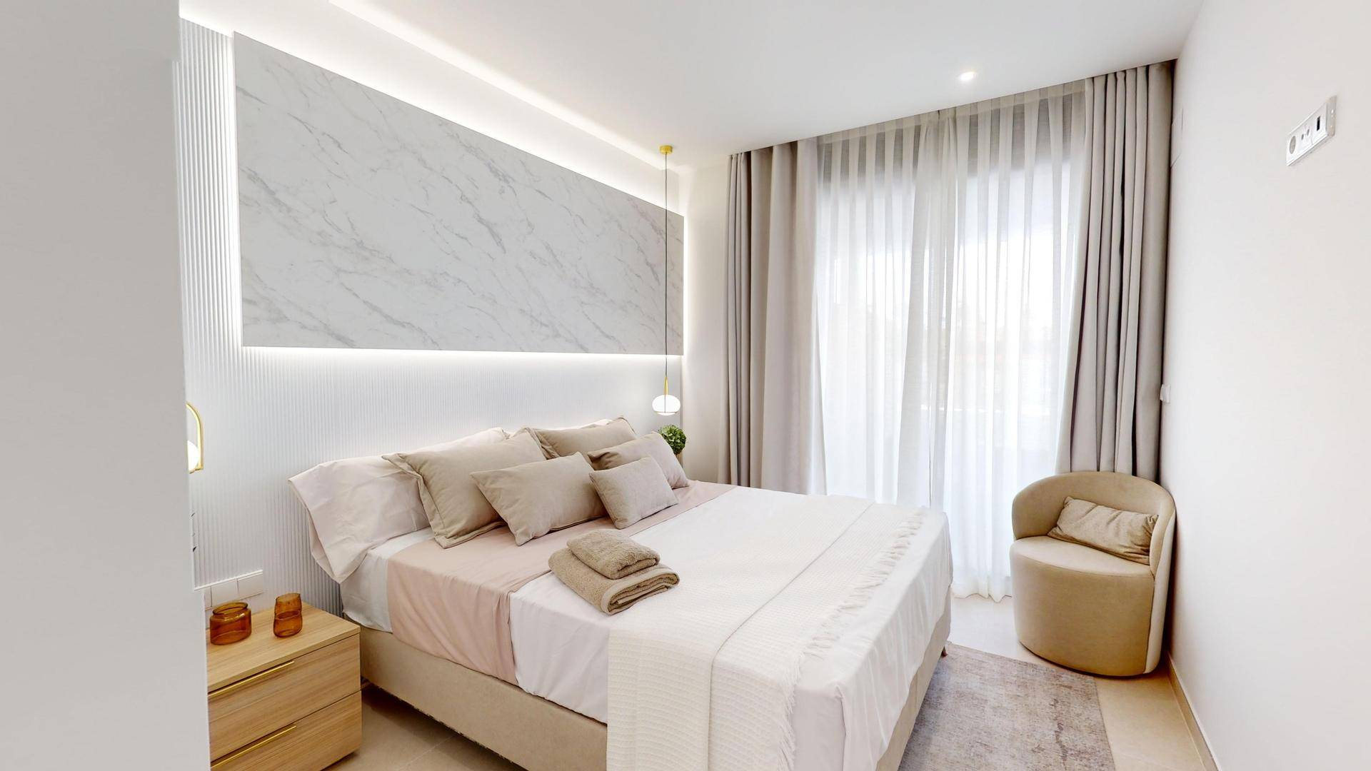 Modernes Schlafzimmer mit elegantem Marmor-Kopfteil, indirekter Beleuchtung und großem Fenster mit Vorhängen.