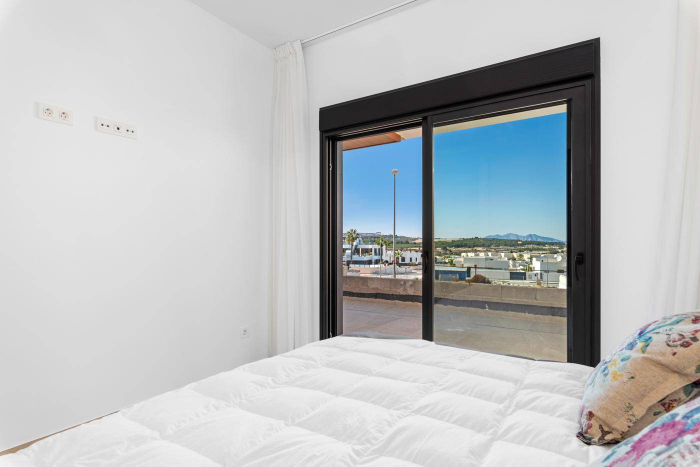 Helles Schlafzimmer mit großem Fenster und weitem Blick auf die Landschaft und Berge.