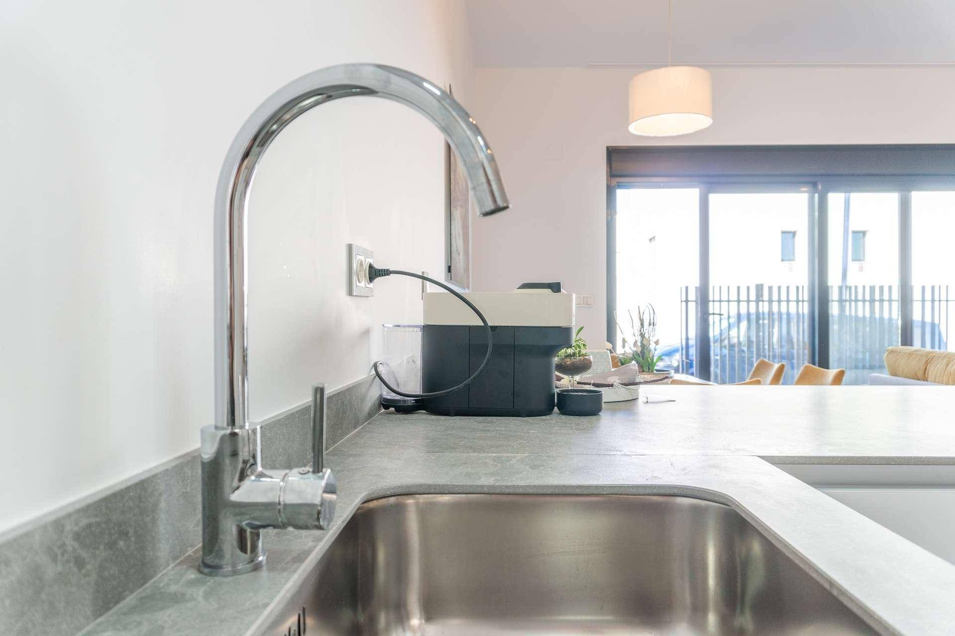 Nahaufnahme der Küchenspüle mit modernem Wasserhahn und Blick auf den Wohnbereich.