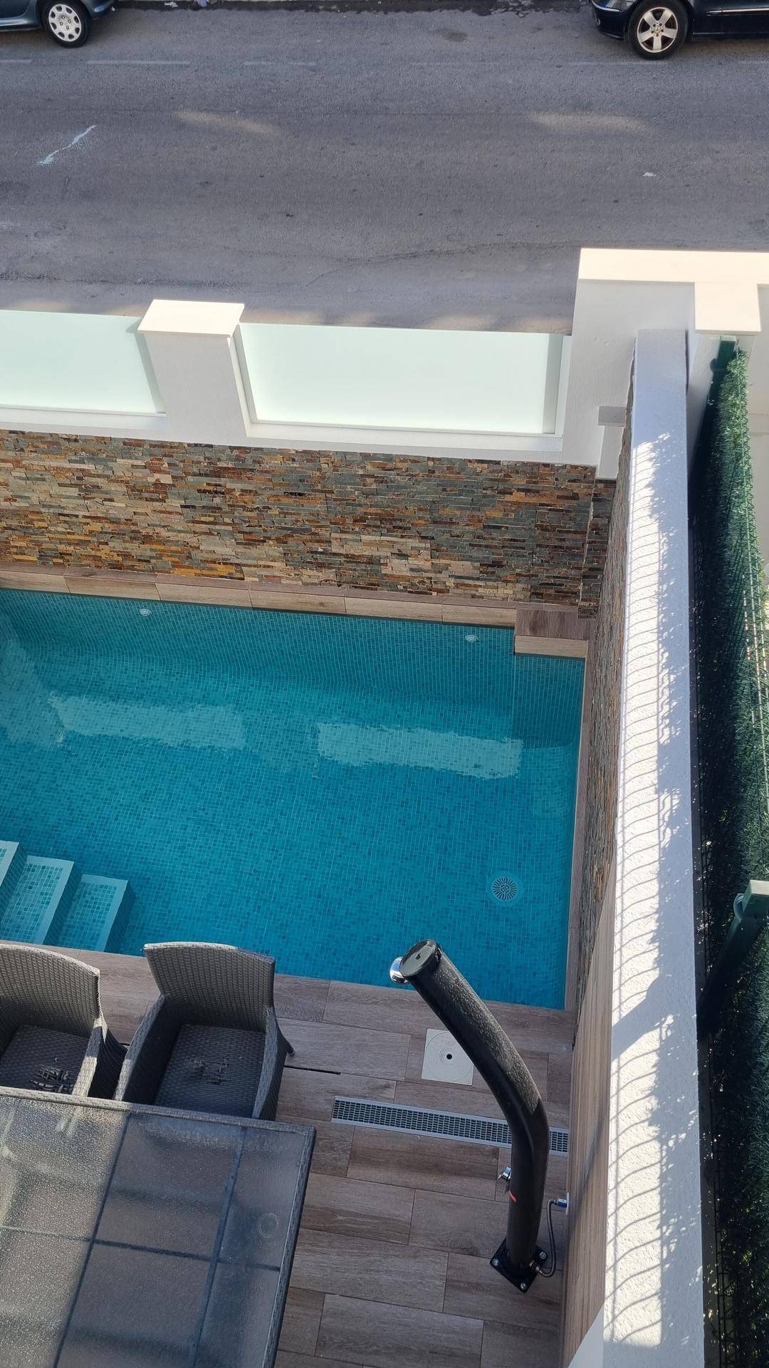 Blick von oben auf den privaten Poolbereich mit Holzterrasse und Sitzgelegenheiten.
