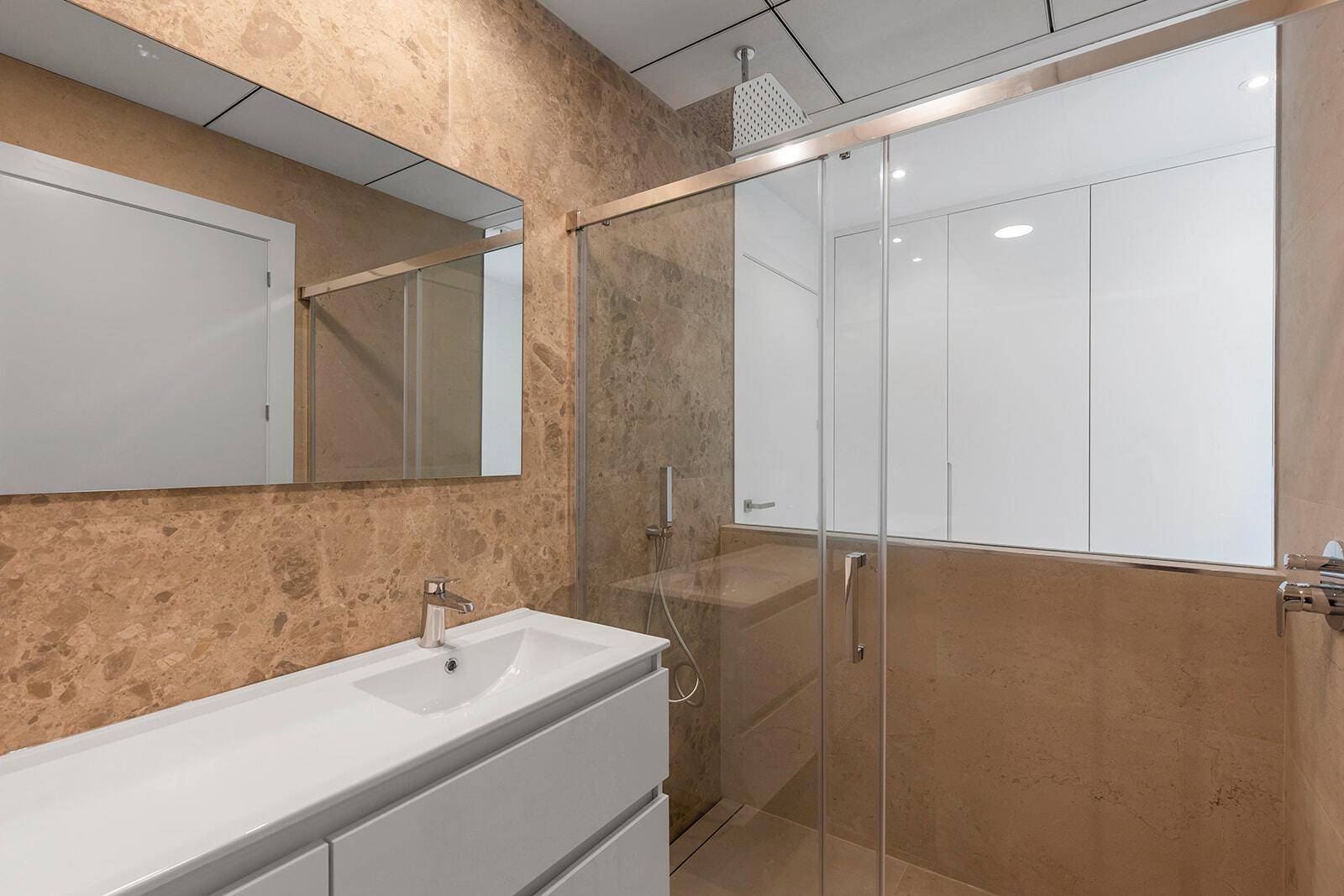 Modernes Badezimmer mit braunen Marmorfliesen, begehbarer Dusche und elegantem Waschbecken.