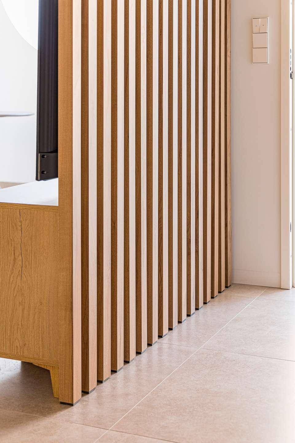 Detailansicht einer modernen Holzlamellenwand, die den Raum stilvoll unterteilt.