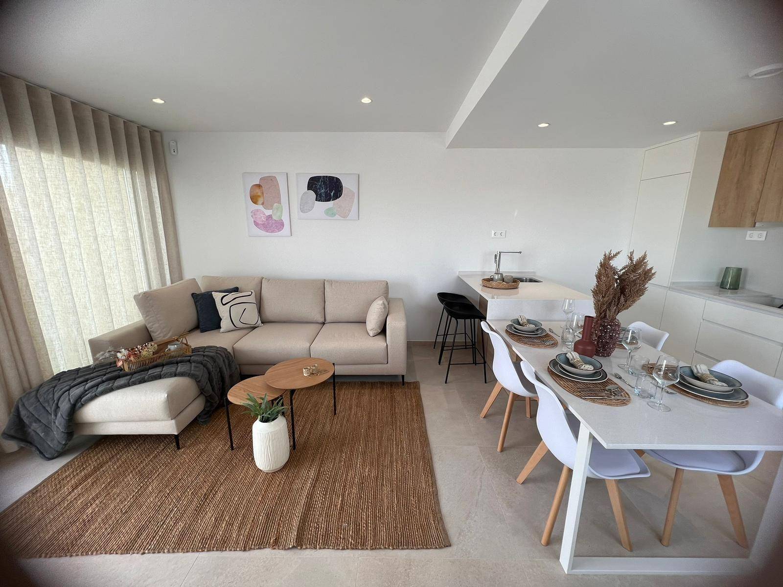 Heller Wohn-Essbereich mit offener Küche, beigem Sofa und modernem Esstisch.