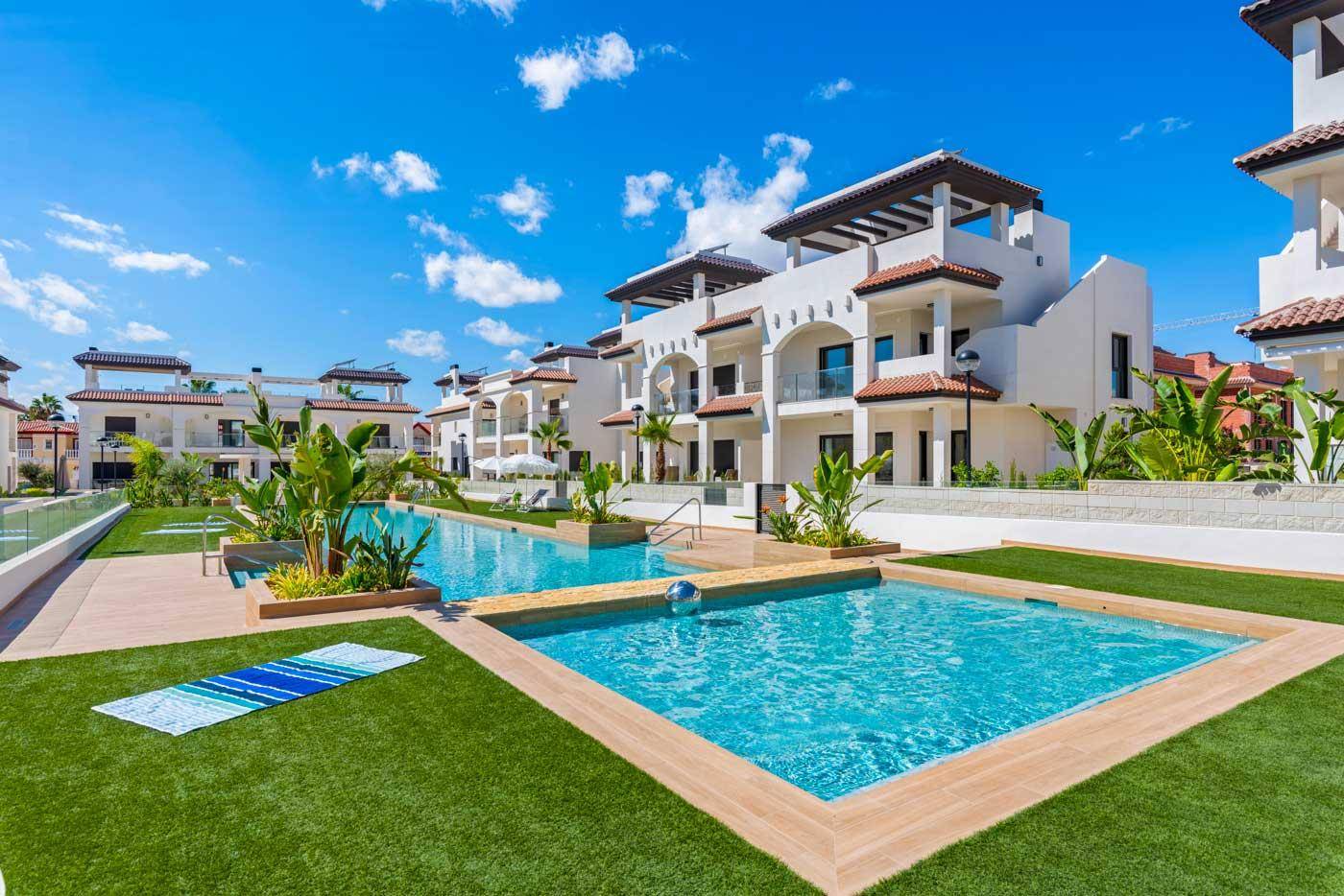 Attraktive Poollandschaft mit Liegeflächen und mediterraner Bepflanzung in einer modernen Wohnanlage.