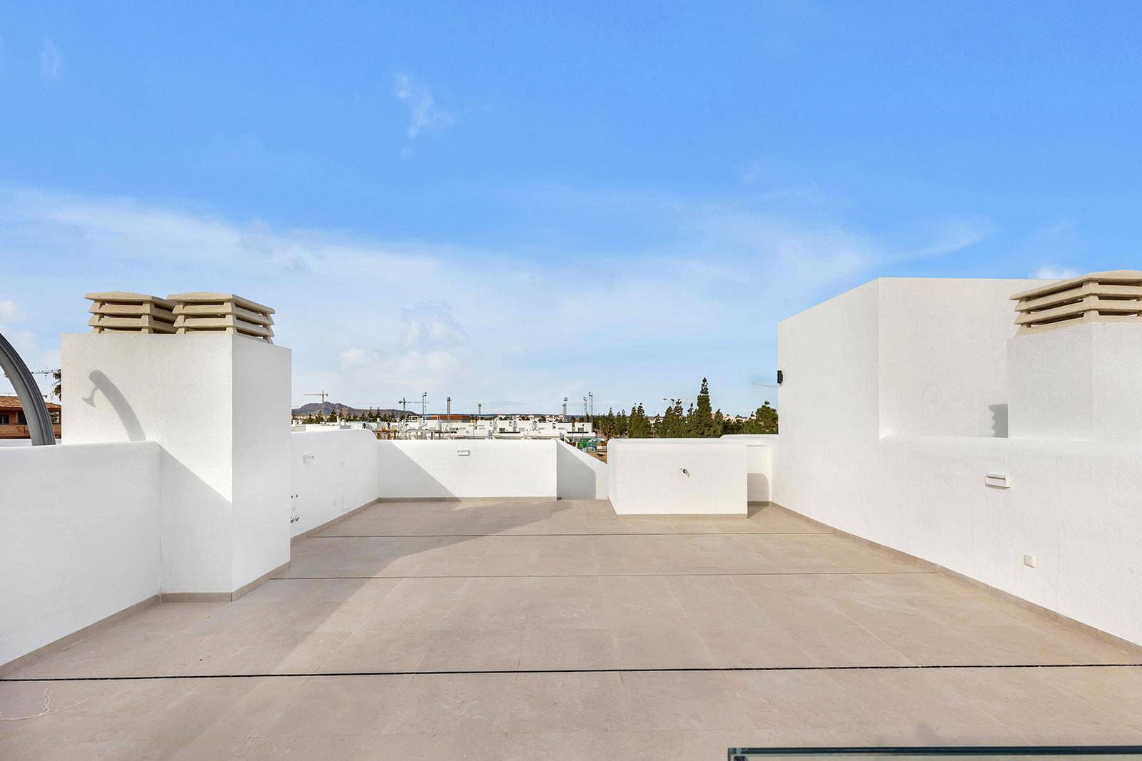 Weitläufige, unmöblierte Dachterrasse mit Blick auf die umliegende Bebauung.