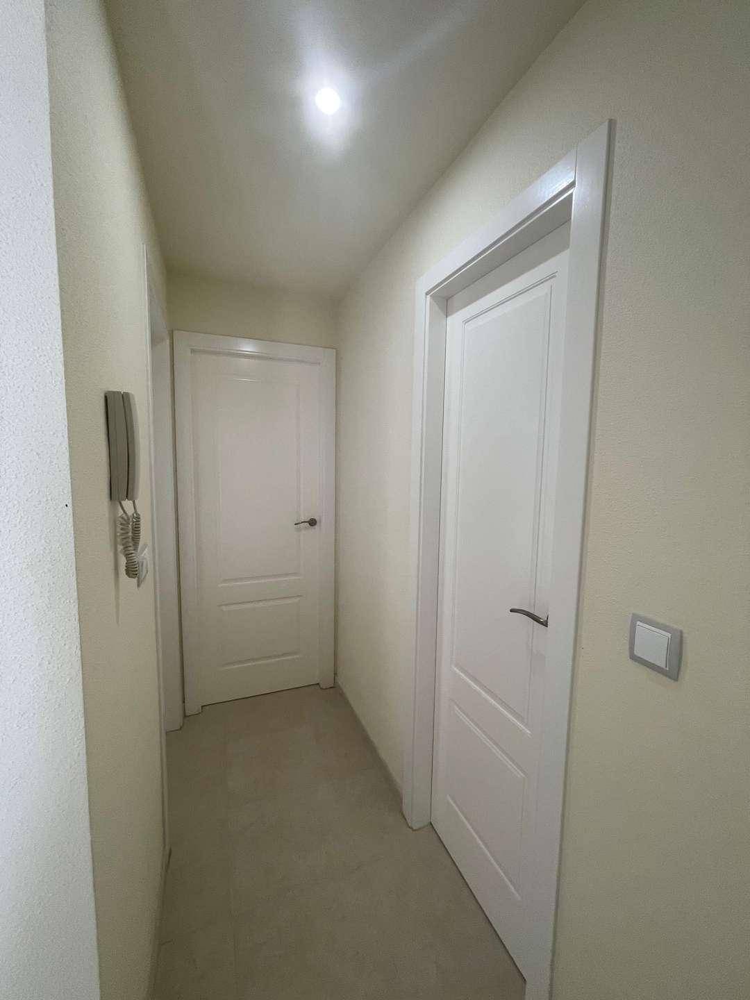 Heller Flur mit weißen Türen, der zu den verschiedenen Räumen der Wohnung führt.