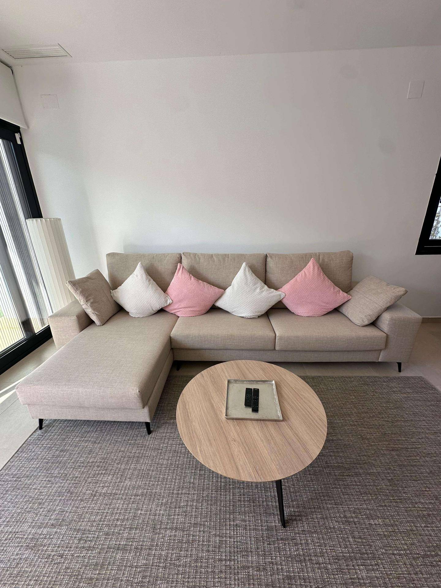 Gemütliches beiges Ecksofa mit Kissen und rundem Couchtisch im Wohnzimmer.