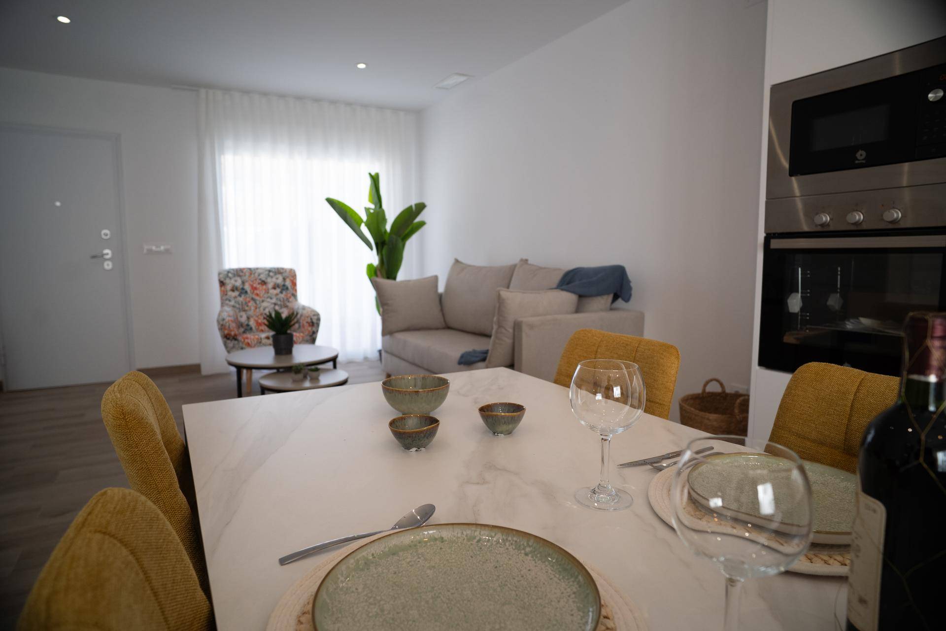 Gemütlicher Essbereich mit gedecktem Tisch und angrenzendem Wohnbereich mit Sofa.