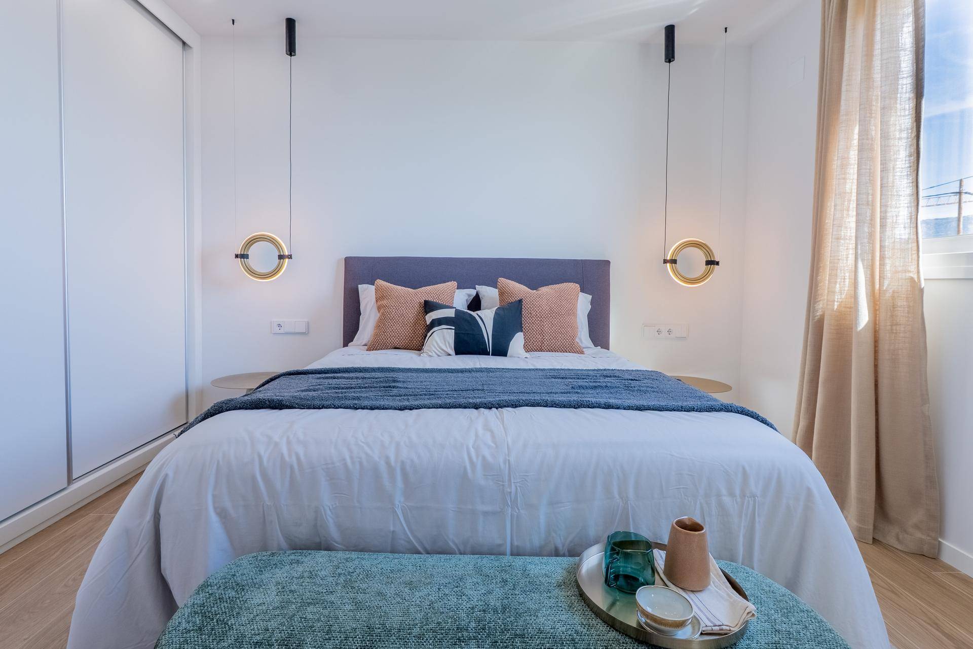 Modernes Schlafzimmer mit Doppelbett, schwebenden Nachttischlampen und Einbauschrank.