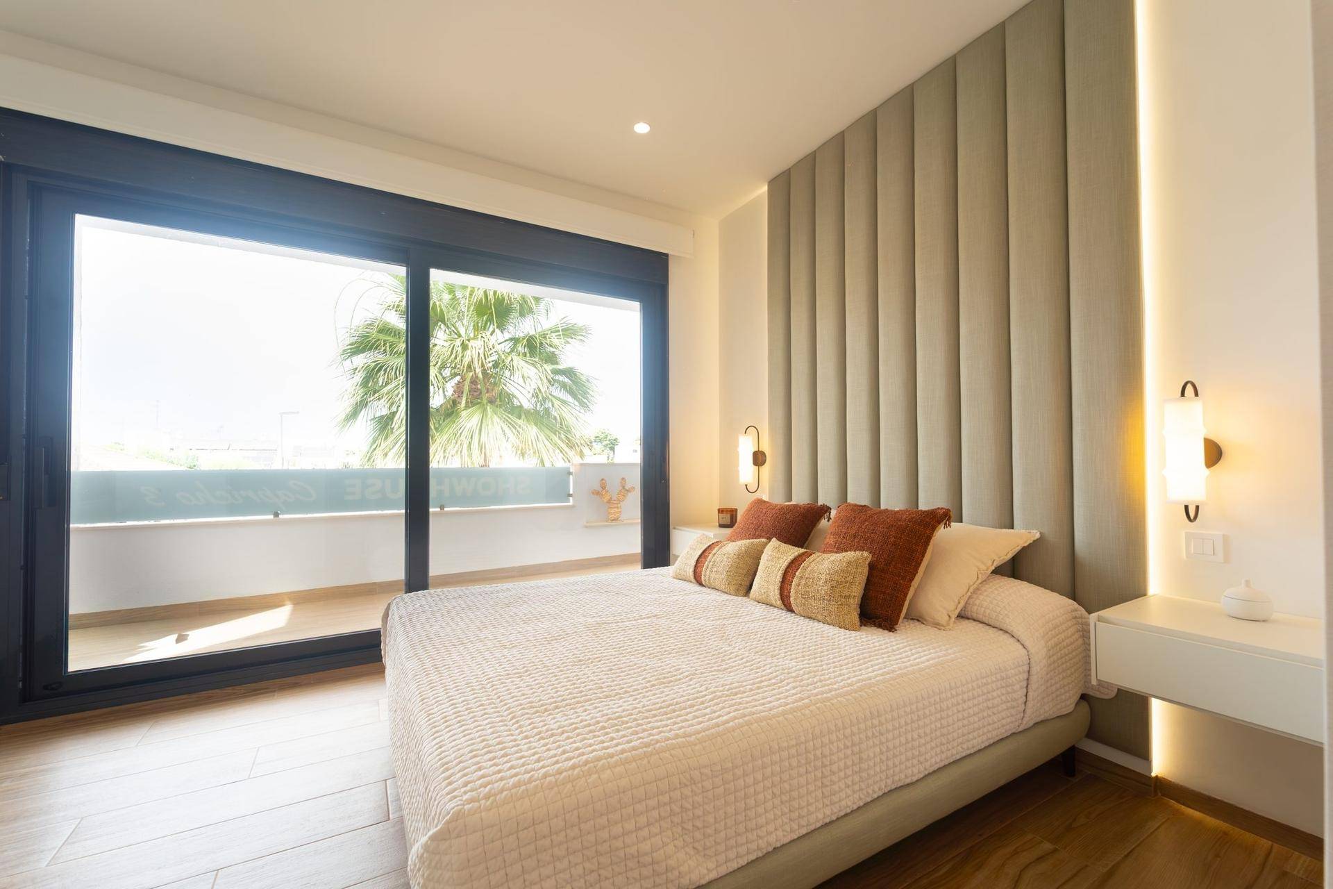 Helles Schlafzimmer mit Doppelbett, stilvollem Kopfteil und großen Fenstern zum Balkon.
