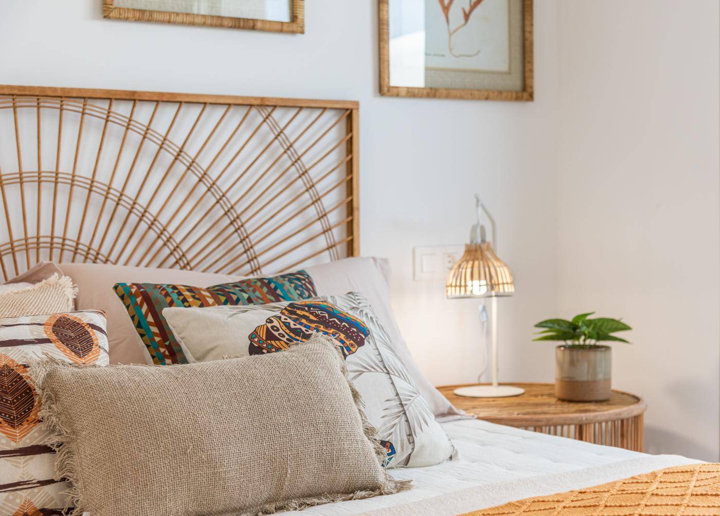 Schlafzimmer mit Rattan-Kopfteil, passendem Nachttisch und warmen Farbakzenten.