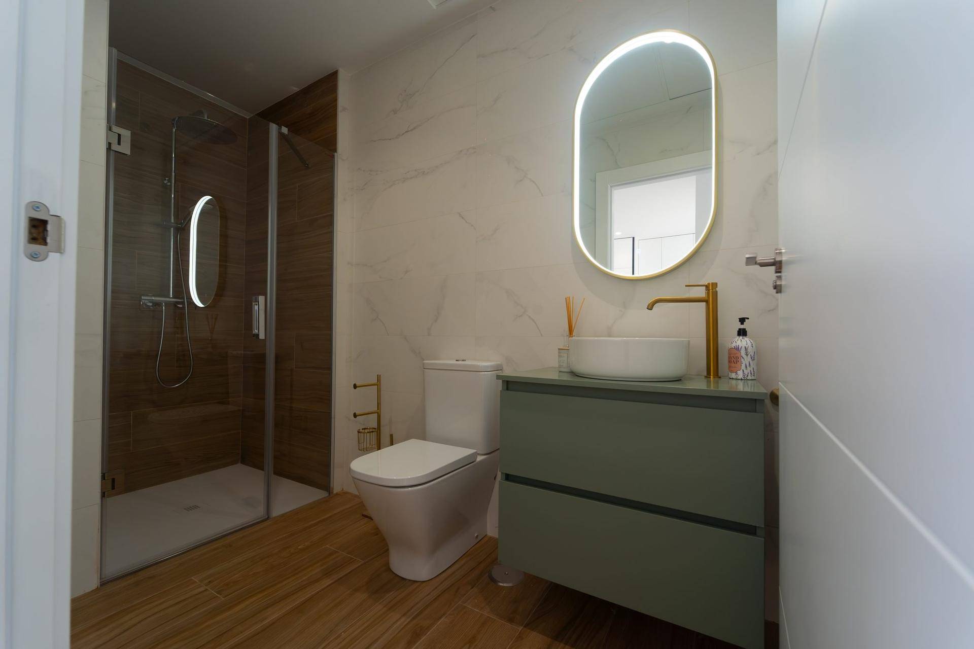 Modernes Badezimmer mit begehbarer Dusche, elegantem Waschtisch und beleuchtetem Spiegel.