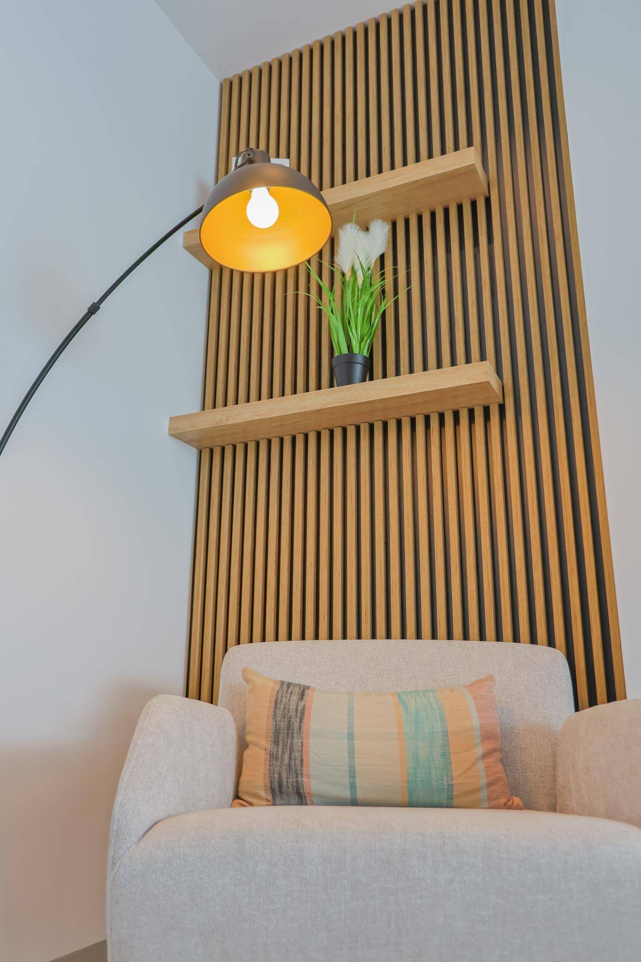 Gemütliche Leseecke mit modernem Sessel, Stehlampe und dekorativer Holzlamellenwand.