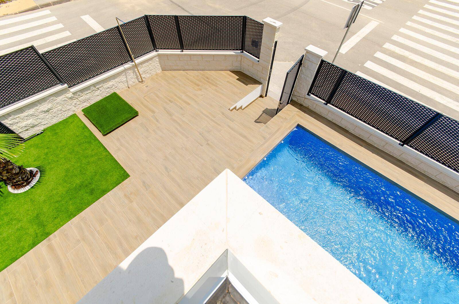 Vogelperspektive des Eingangsbereichs mit Pool, Terrasse und angrenzender Straße.
