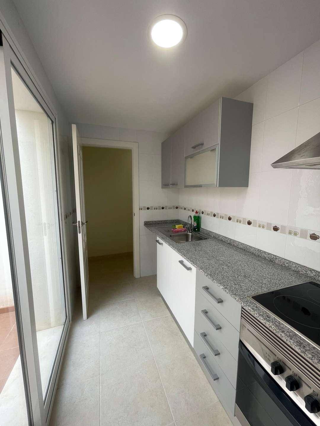 Funktionale Küche mit weißen und grauen Schränken, Granitarbeitsplatte und Zugang nach draußen.