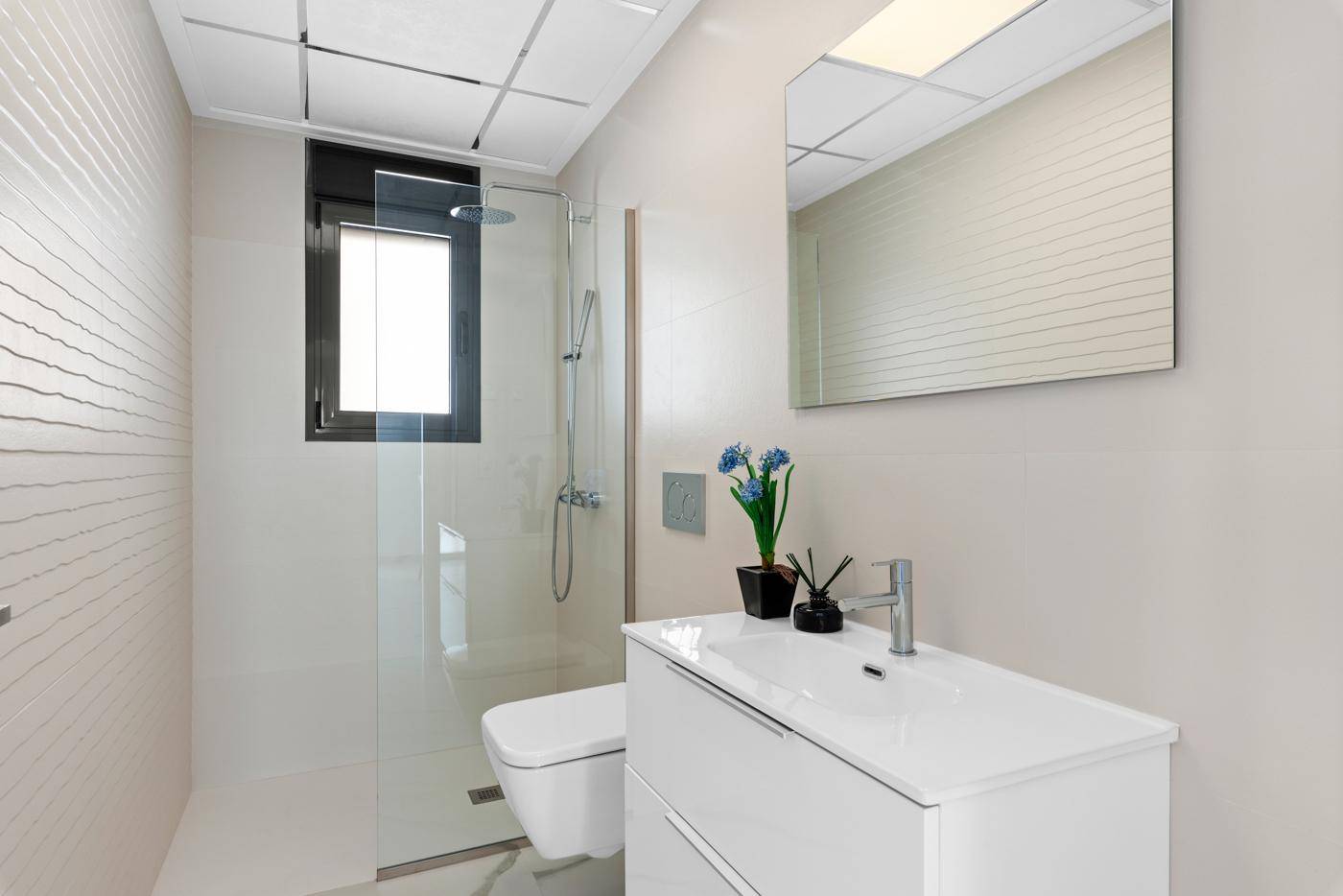 Modernes Badezimmer mit Duschkabine, wandhängendem WC und großem Spiegel.