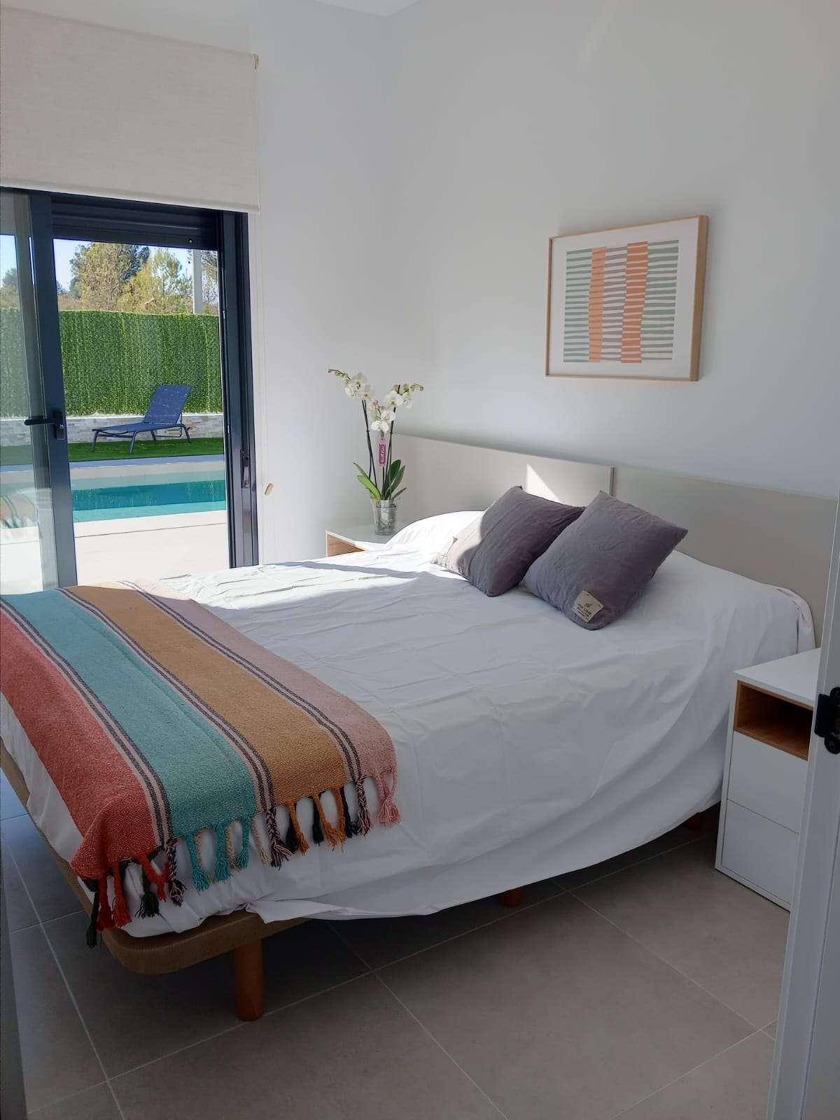 Helles Schlafzimmer mit farbenfroher Decke und direktem Zugang zum Poolbereich.