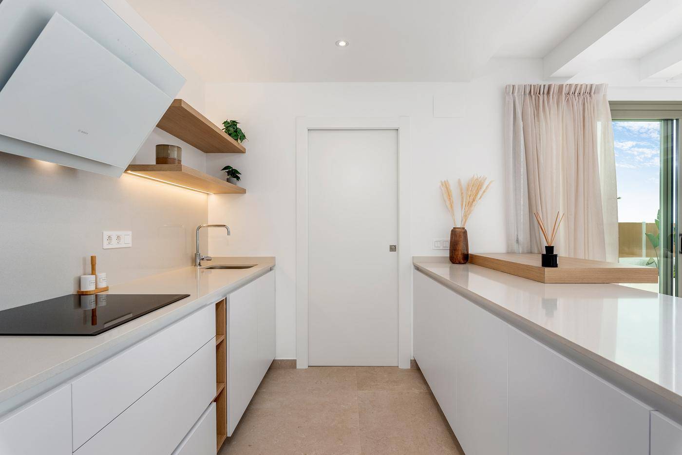 Moderne Küche mit weißen Schränken, Holzdetails und integrierten Geräten.
