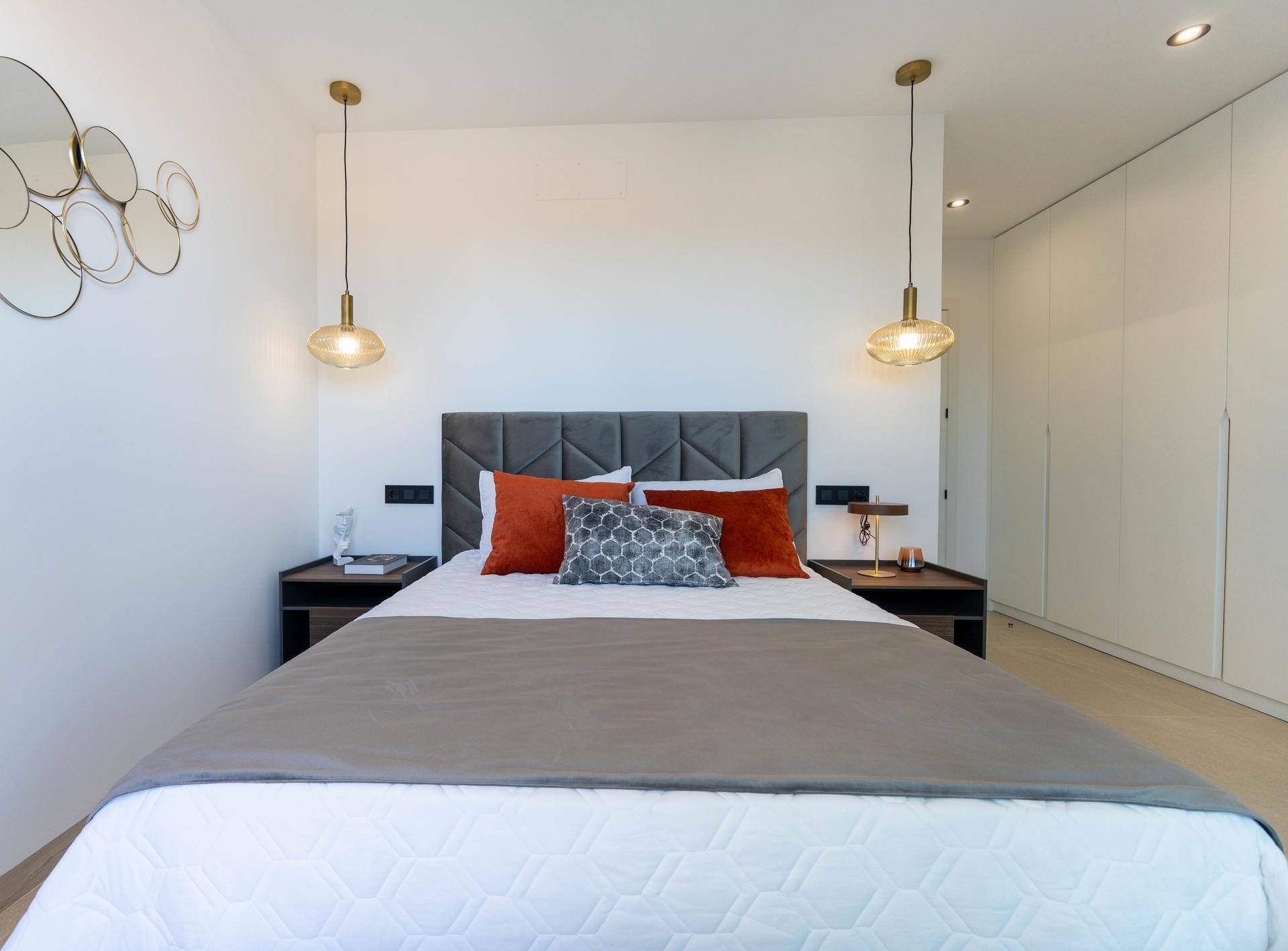 Modernes Schlafzimmer mit großem Bett, gepolstertem Kopfteil und integrierten Schränken.