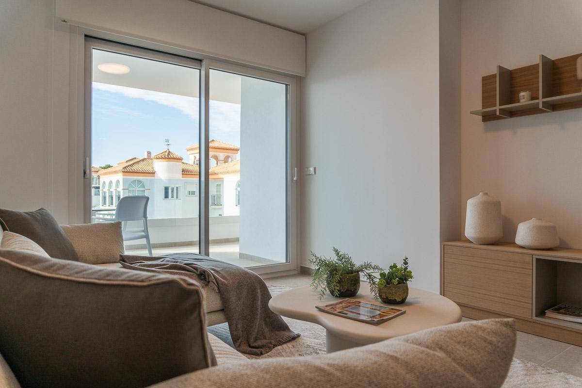 Gemütlicher Wohnbereich mit beigem Sofa und Couchtisch, mit Blick auf den Balkon.