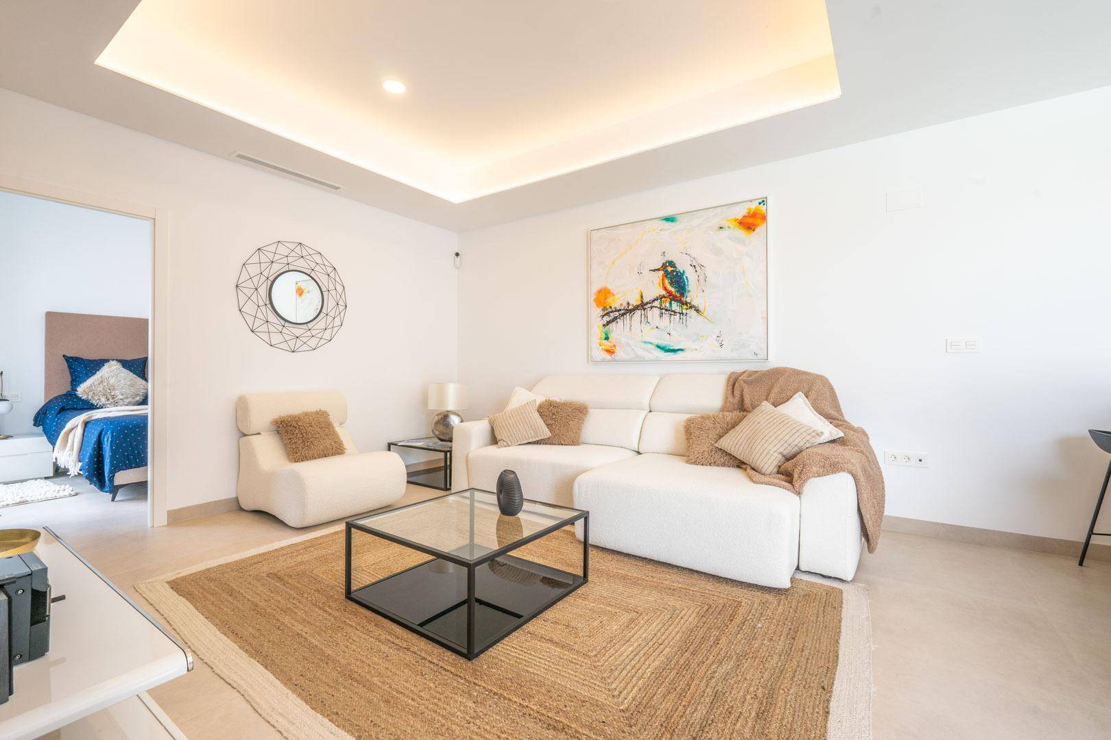 Helles Wohnzimmer mit bequemer Couch, modernem Teppich und Kunst an der Wand.