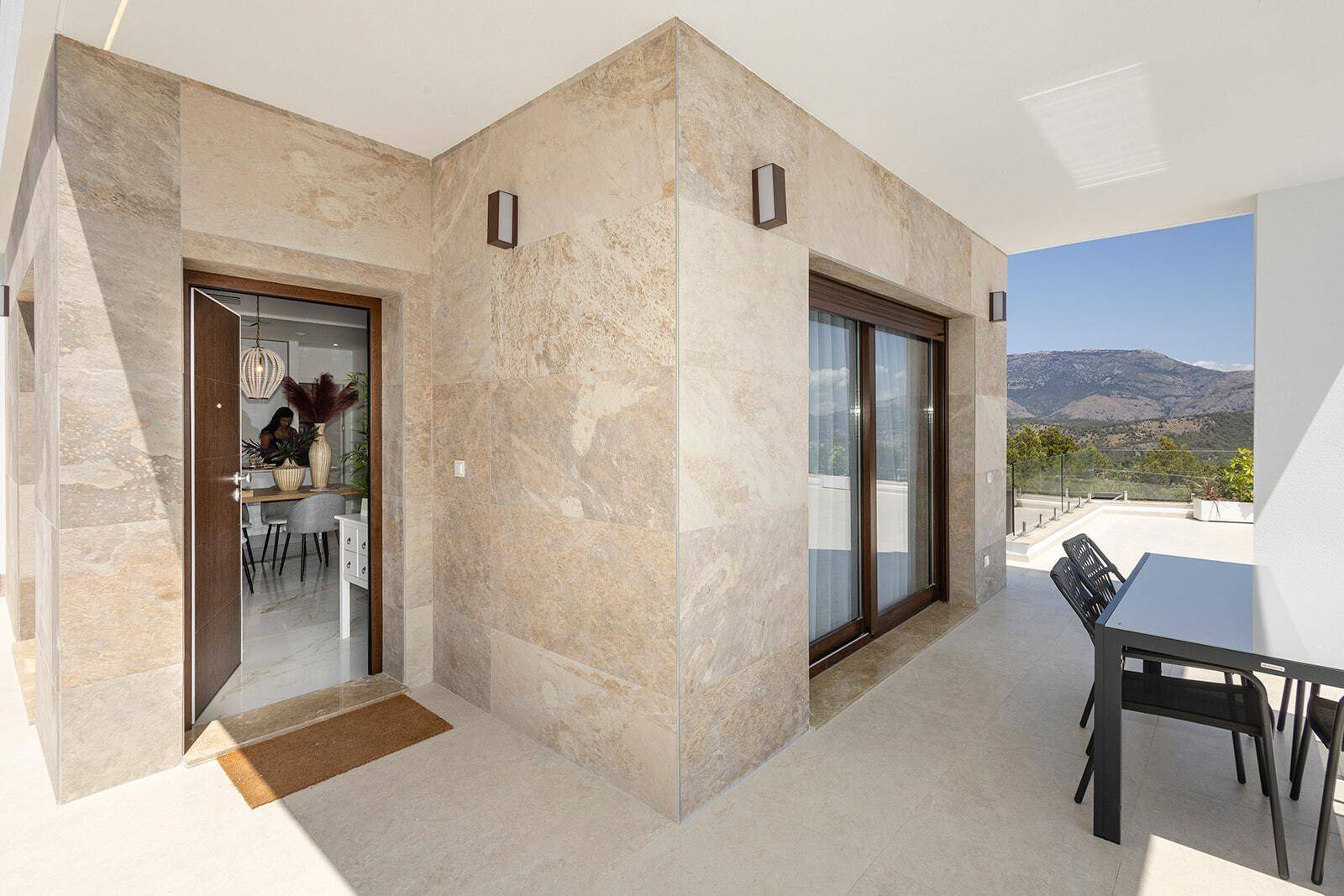 Eingangsbereich der Villa mit überdachter Terrasse, Fliesenboden und Bergblick.