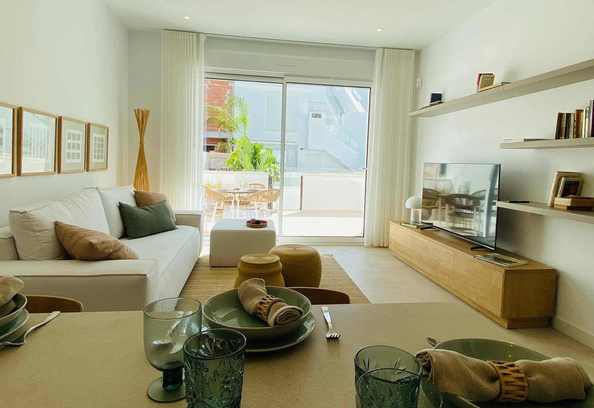 Heller Wohn- und Essbereich mit Zugang zu einer möblierten Terrasse und modernen Möbeln.