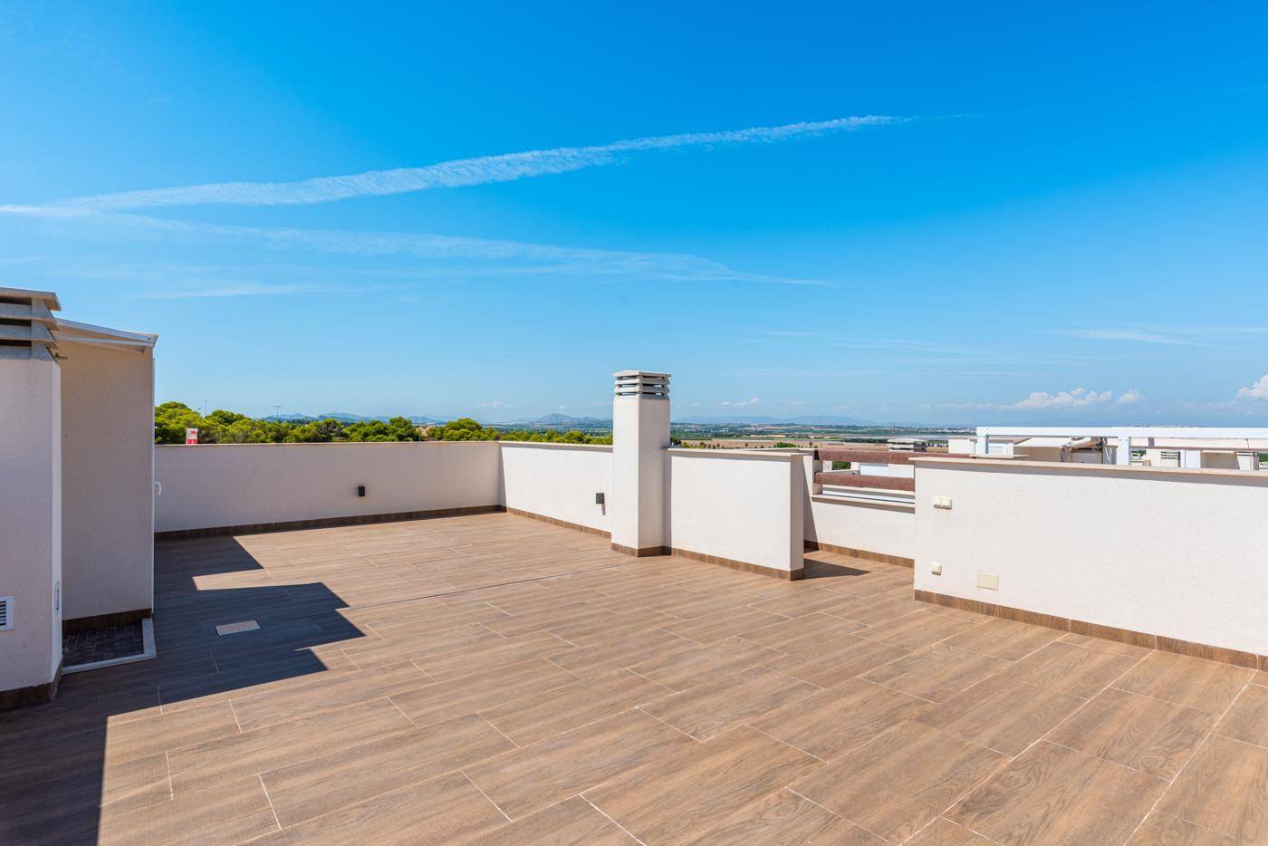 Weitläufige Dachterrasse mit niedrigen Mauern und Panoramablick auf die Umgebung.