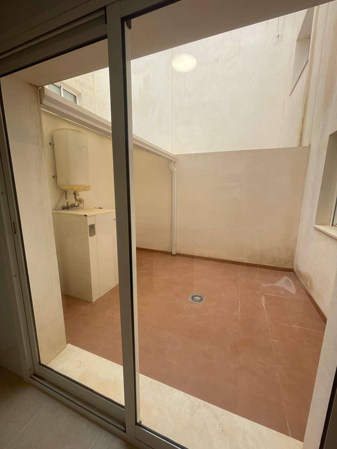Kleiner, gefliester Innenhof mit Warmwasserbereiter, dient als praktischer Außenbereich.