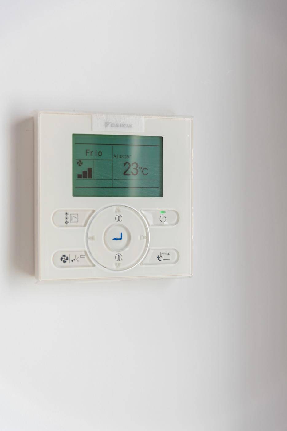 Steuerungspanel für die Klimaanlage mit digitaler Anzeige an einer weißen Wand.