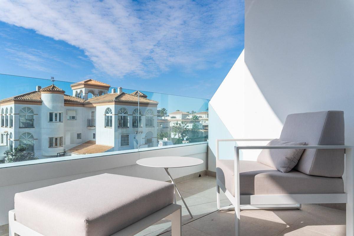 Heller Balkon mit bequemen Loungemöbeln und Panoramablick über die Dächer der Stadt.