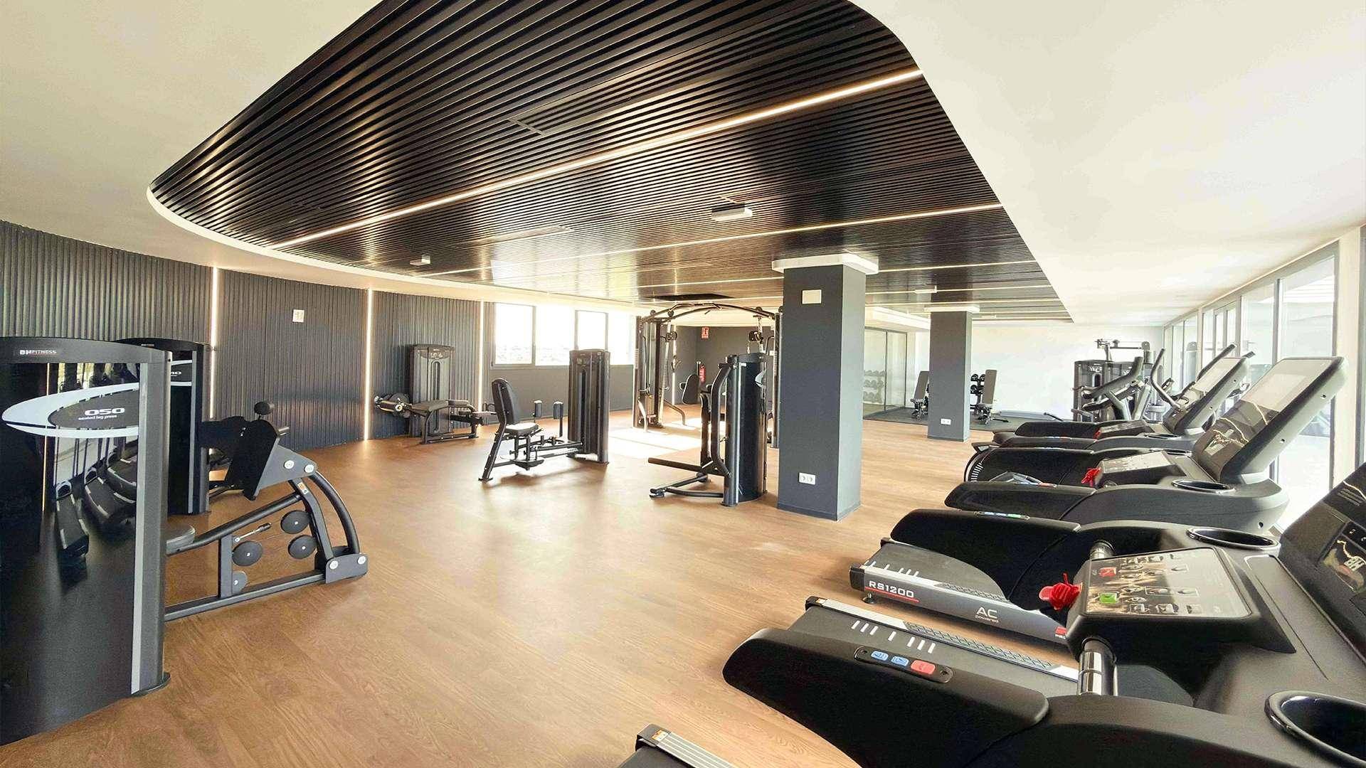 Geräumiger Fitnessraum mit einer Vielzahl an modernen Trainingsgeräten und Holzboden.