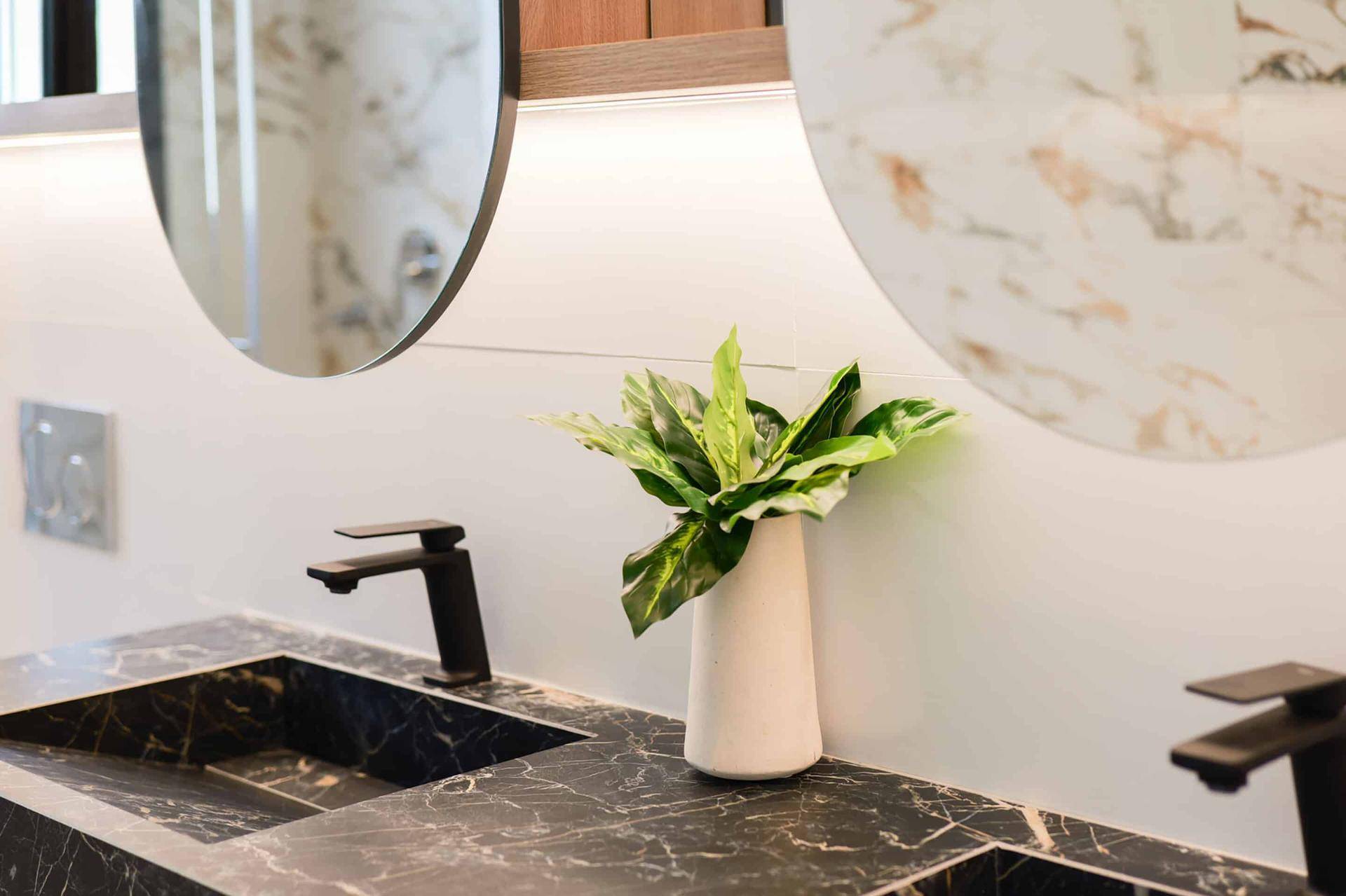 Elegantes Badezimmer mit Doppelwaschbecken und schwarzer Marmorarbeitsplatte.