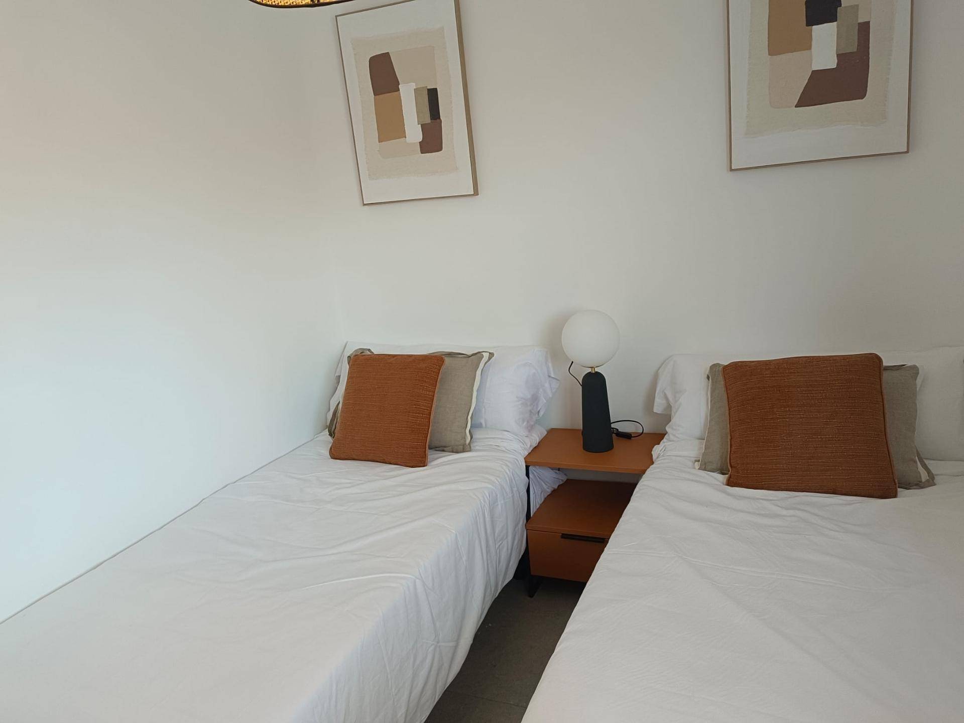 Helles Schlafzimmer mit zwei Einzelbetten, Nachttisch und moderner Dekoration.