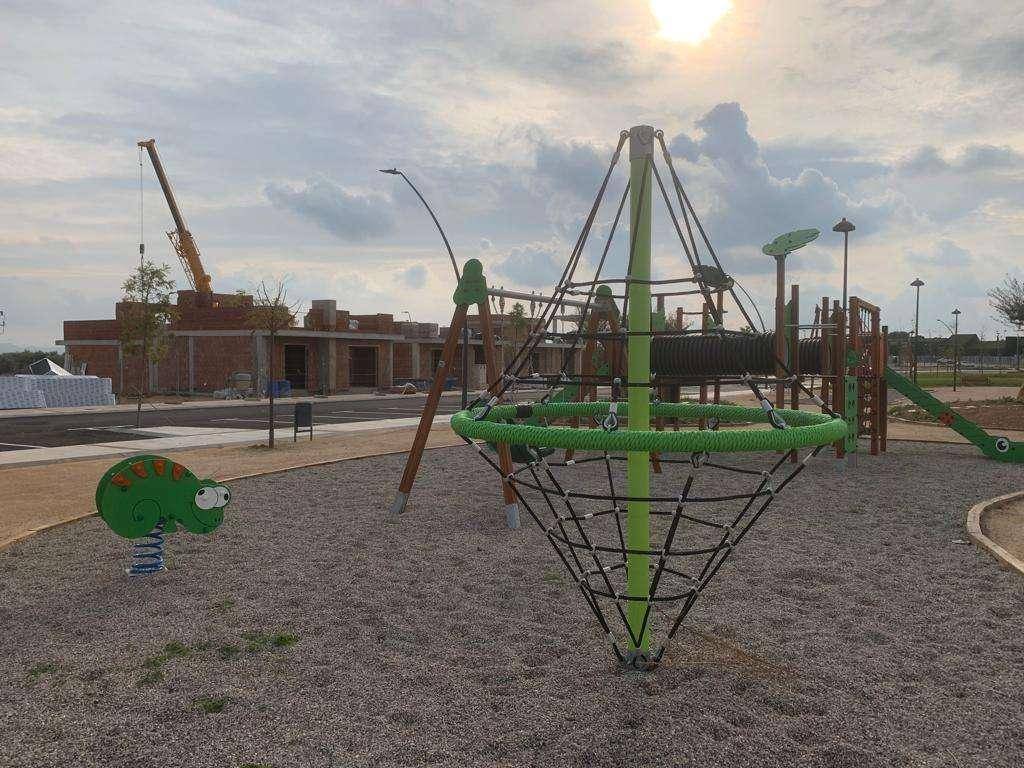 Moderner Spielplatz mit Klettergerüst und Rutsche in einer neuen Wohngegend.
