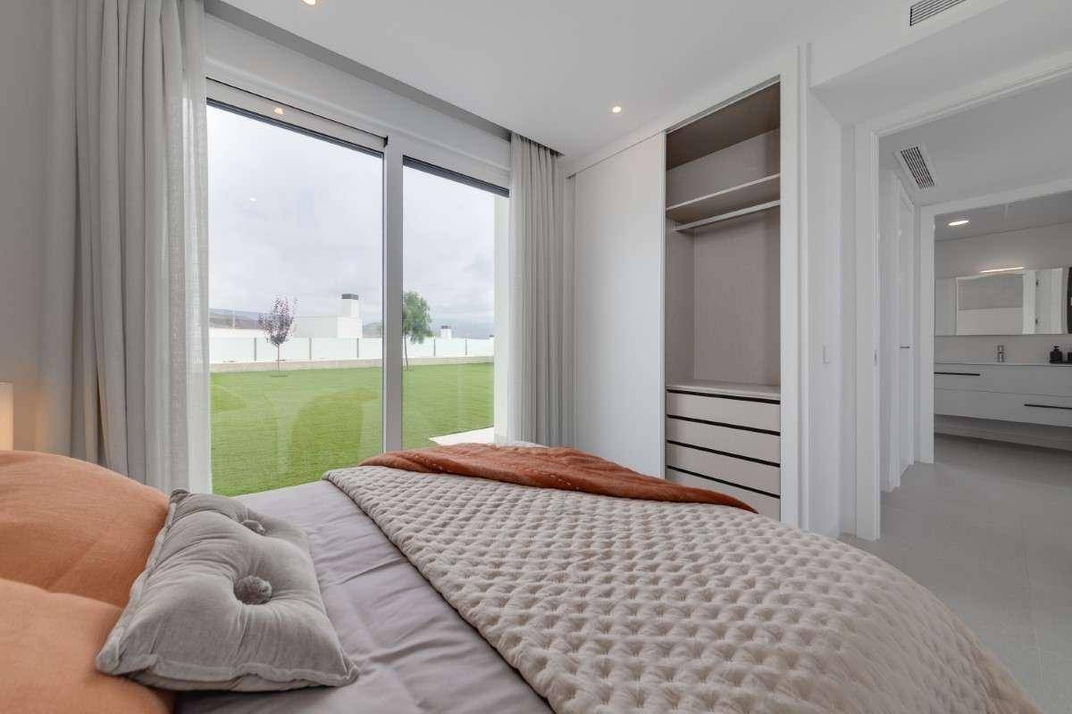 Helles Schlafzimmer mit großen Fenstern, Einbauschrank und Blick auf den grünen Garten.