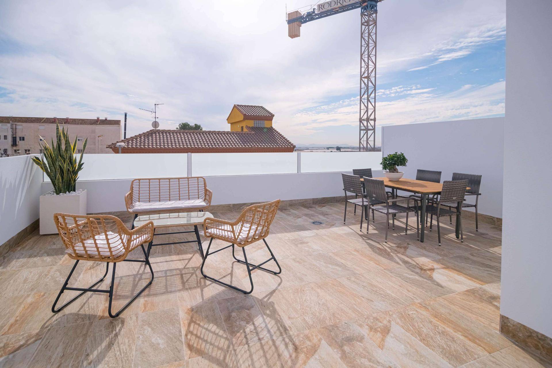 Weitläufige Dachterrasse mit Essbereich und Lounge-Möbeln unter blauem Himmel.