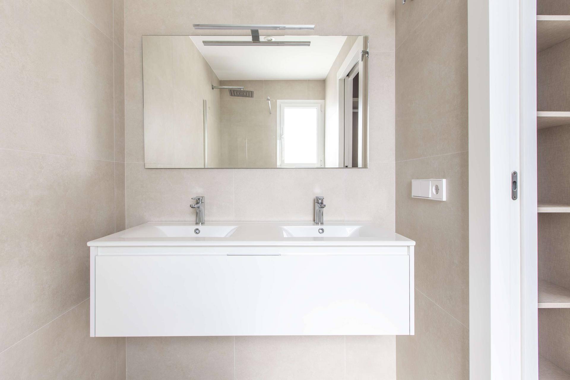 Modernes Badezimmer mit Doppelwaschbecken, großem Spiegel und Duschbereich.