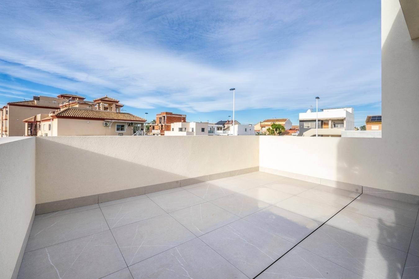 Geräumige Dachterrasse mit Fliesenboden und hohen Brüstungen, bietet einen weiten Blick auf die Umgebung.