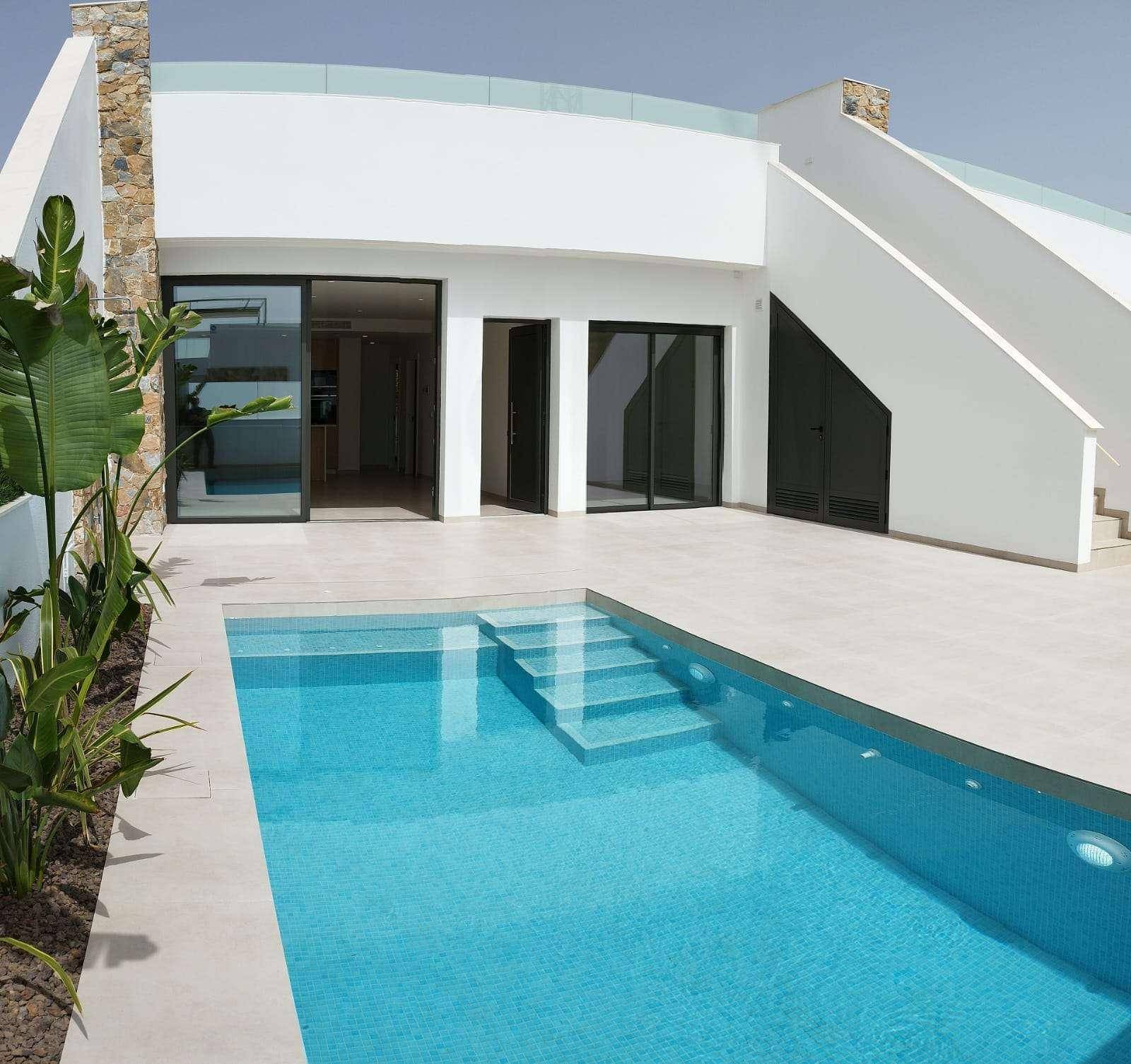 Außenansicht des Hauses mit modernem Pool und breiter Terrasse unter blauem Himmel.