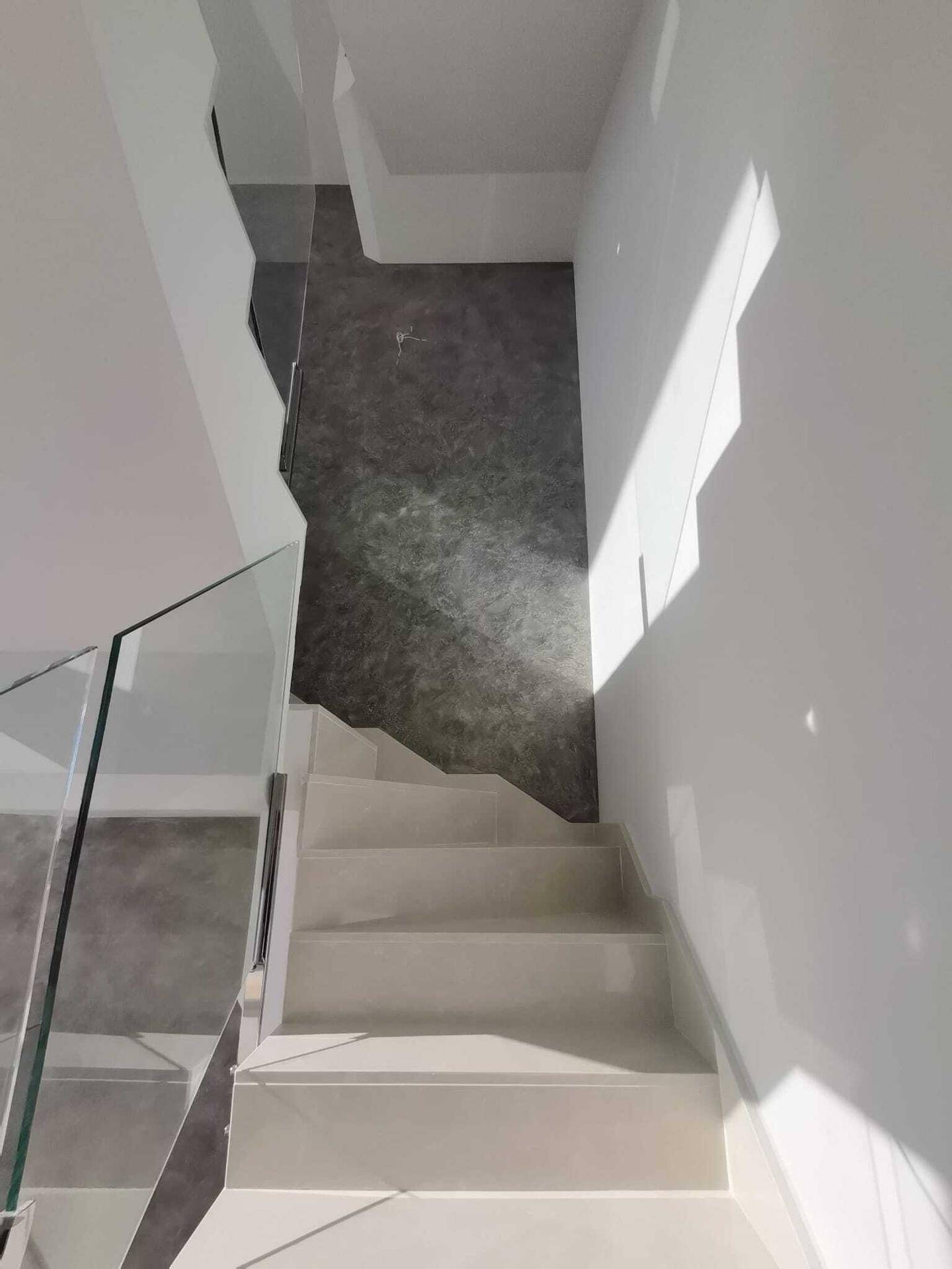 Moderne Treppe mit Glasgeländer und hellem Fliesenboden, die die Etagen elegant verbindet.