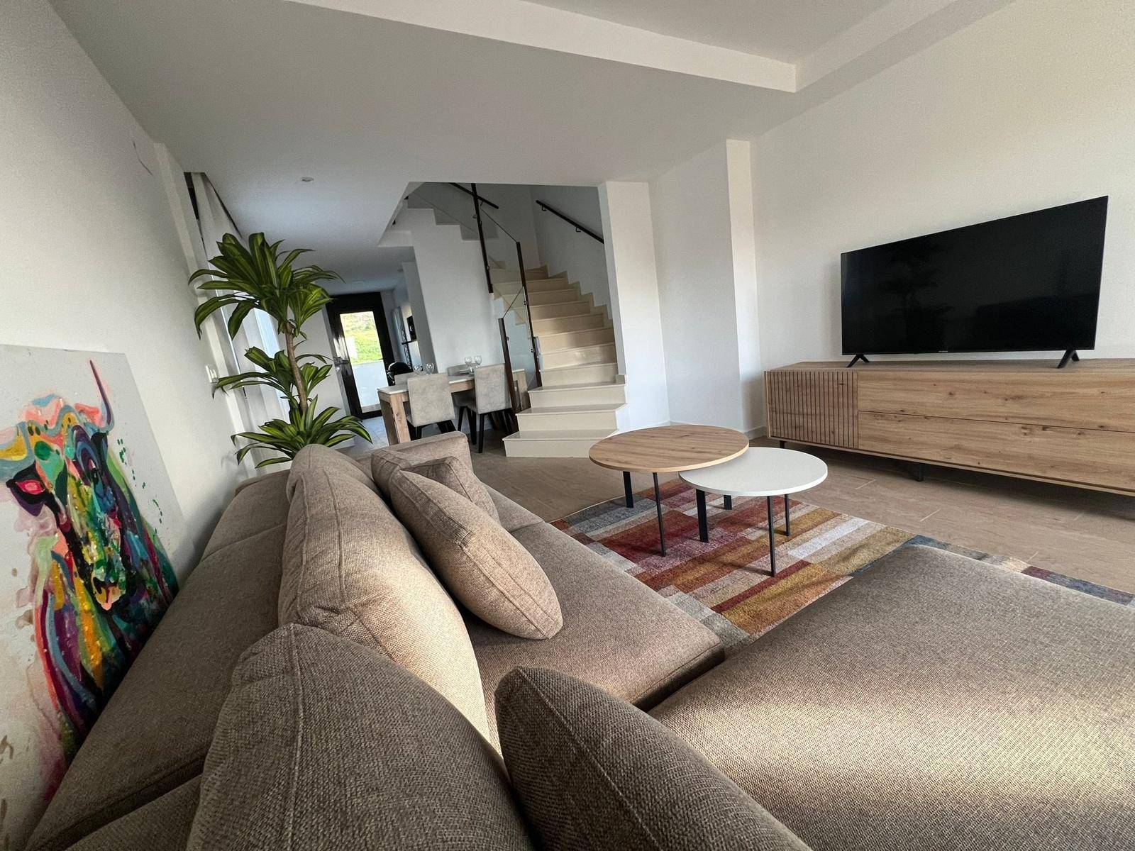 Geräumiger Wohnbereich mit modernem Sofa, TV-Möbel und Treppe zum Obergeschoss.