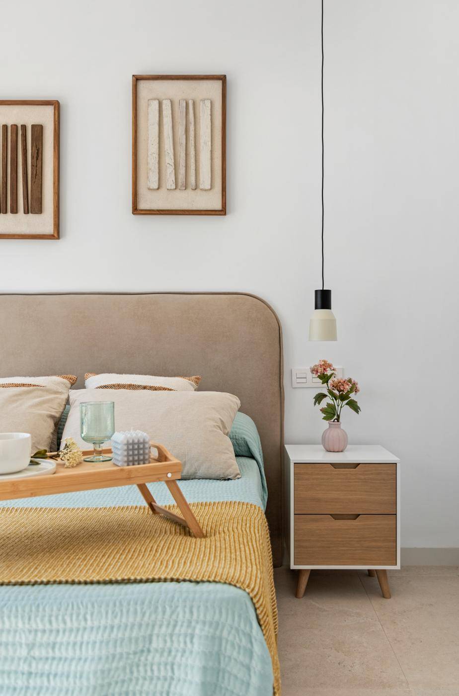 Schlafzimmer mit gepolstertem Kopfteil, modernem Nachttisch und minimalistischer Pendelleuchte.