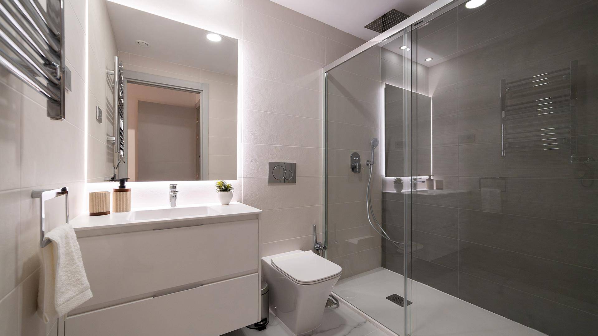Modernes Badezimmer mit begehbarer Dusche, beleuchtetem Spiegel und Wand-WC.
