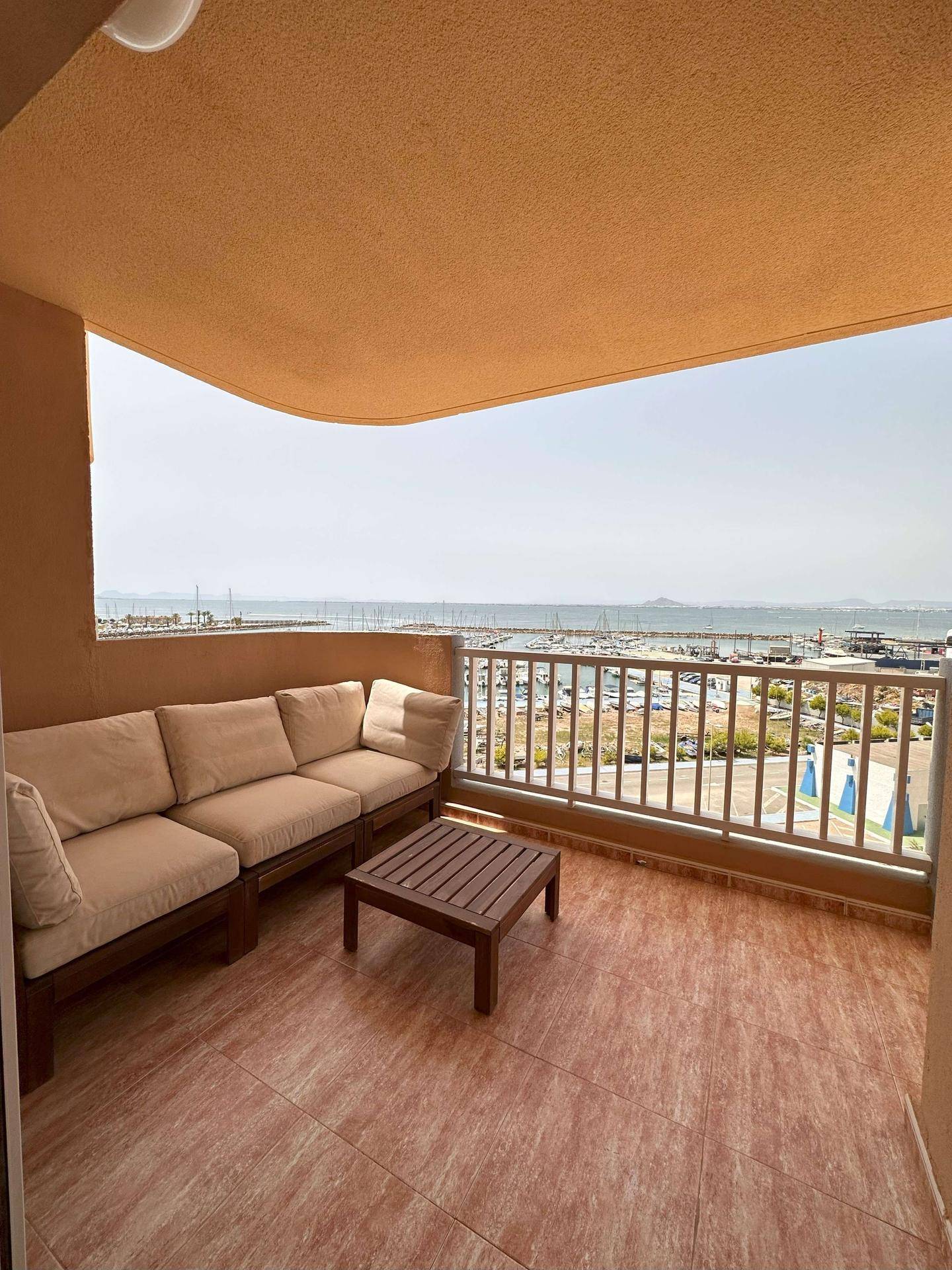 Geräumiger Balkon mit bequemen Loungemöbeln und Panoramablick auf den Yachthafen und das Meer.