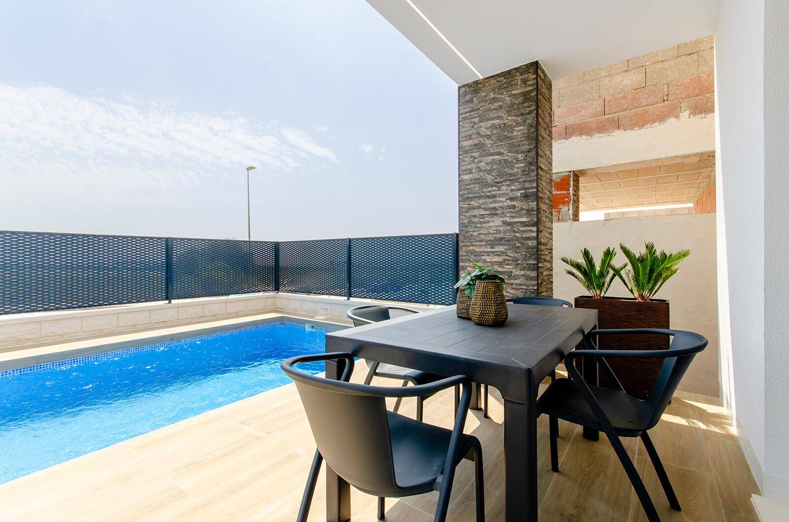 Überdachte Terrasse mit modernem Esstisch und Stühlen direkt am Poolbereich.