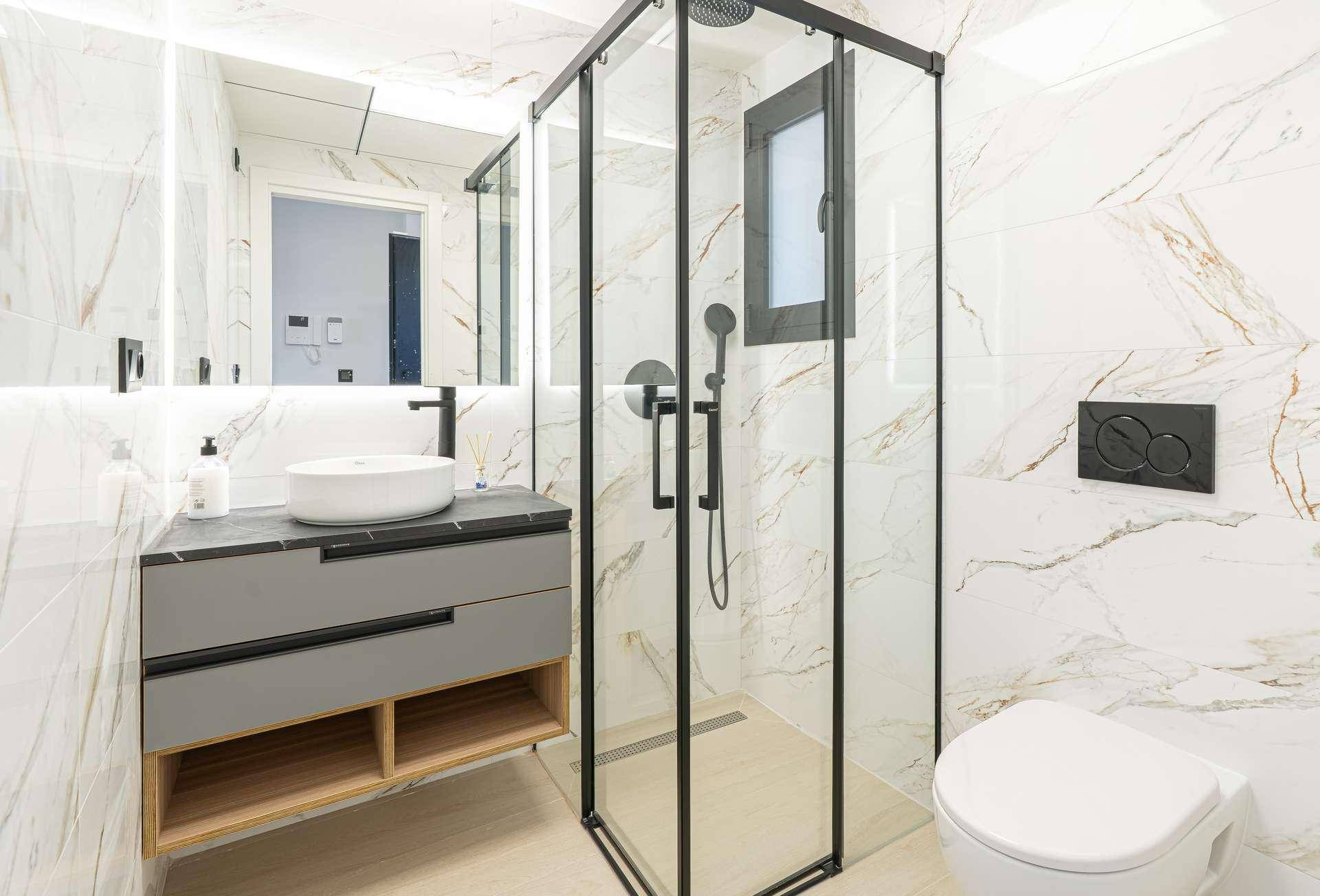 Modernes Badezimmer mit begehbarer Dusche, eleganten Marmorfliesen und minimalistischem Design.